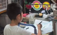 爆红！武汉江汉路闹市水果摊，一小学生背对人群专注写作业，全程头都不回，网友：我娃一张纸掉地上都要看